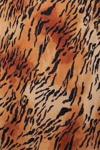 Tessuto con stampa animale caratterizzato da uno sfondo arancione e beige con strisce marrone scuro e nere. La texture appare morbida e fluida.