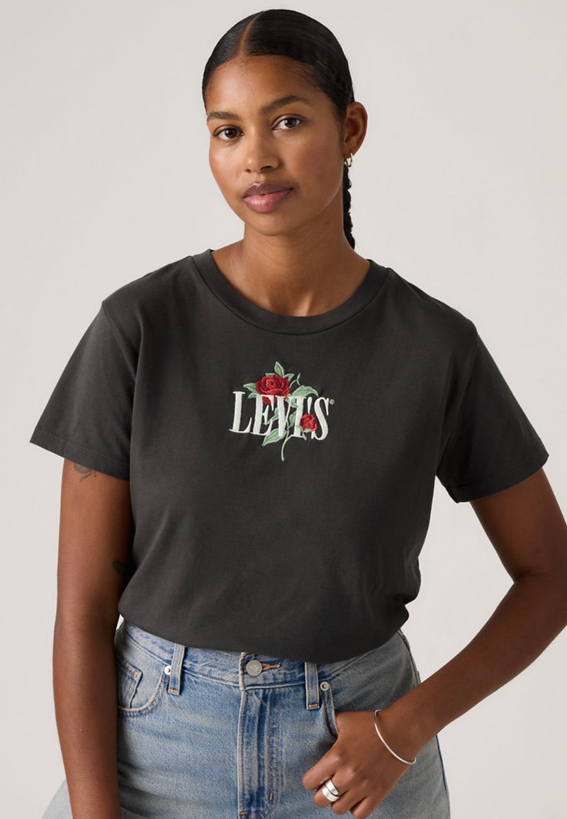 Camiseta negra de algodón con un diseño frontal de rosas rojas y el texto blanco "LEVI'S", con un cuello redondo clásico y mangas cortas.