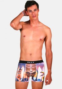 Boxers pour hommes avec un imprimé vibrant sur le thème de la plage featuring des planches de surf et un totem sculpté. Fabriqués en tissu doux avec une ceinture noire contrastante.