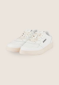 Sneakers in pelle bianca con punta perforata, lacci beige e suola in gomma. Presentano un piccolo logo sul lato e elementi di design semplici.