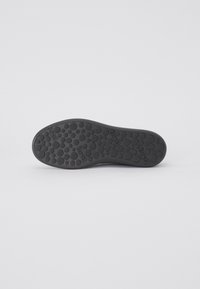 Sole in gomma nera con un motivo a punti per garantire aderenza, con il marchio in rilievo ben visibile. Bordo liscio e forma curva per il massimo comfort.