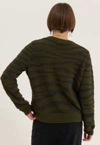 Olivengrüner Pullover mit dunklem Streifenmuster, strukturiertem Stoff, gerippten Bündchen und Saum, Rundhalsausschnitt und einem lässigen Schnitt.