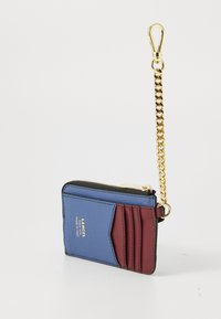 Petit porte-cartes rectangulaire en cuir bleu et bordeaux avec une fermeture éclair dorée et un clip de chaîne dorée attaché.