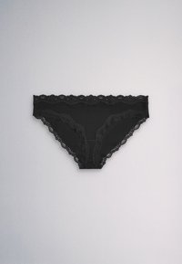 Black lace-trimmed women’s bikini underwear lying flat on a light gray background.