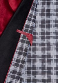 Czarna i czerwona tkanina o teksturowanej powierzchni; wewnątrz szara z naprzemiennymi czarnymi wzorami w kratkę i przekątnymi liniami.