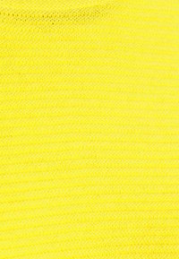 Tissu tricoté jaune vif avec une texture lisse et un motif uniforme, présentant des brins entrelacés créant une apparence homogène.