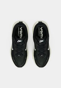 Zapatillas deportivas negras con parte superior texturizada, diseño con cordones y acentos en blanco contrastantes en la suela y en los logos. Cuenta con una plantilla acolchada.