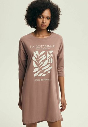 Brązowa sukienka do kolan z rękawami o długości do łokcia. Z białą grafiką liścia i napisem "LA BOTANIQUE" oraz "Beaute des Plantes."