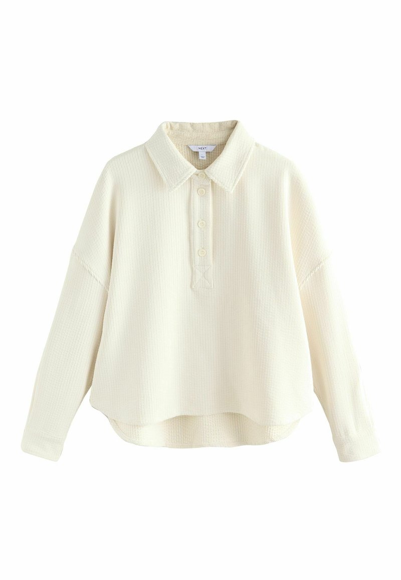 Krämfarvet, struktureret pullover skjorte med kravehalsudskæring, frontknaplukning og let overdimensioneret pasform. Korte længde.