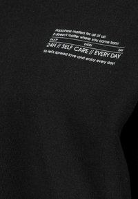 Zwarte sweatshirt met witte bedrukte tekst, voorzien van motiverende zinnen en een eenvoudig ontwerp. Gemaakt van zachte, gestructureerde stof.