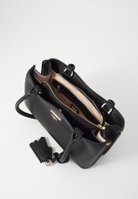 Černá kožená kabelka s pevnou strukturou, vybavená dvěma horními úchyty, zipovou přihrádkou a odnímatelným přívěskem na klíče. Vnitřek má světle hnědou podšívku.