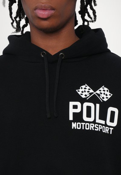 Melna kapuze ar auklu, ar baltu tekstu "POLO MOTORSPORT" un krustotiem šaha karogiem uz krūtīm. Kokvilnas materiāls.