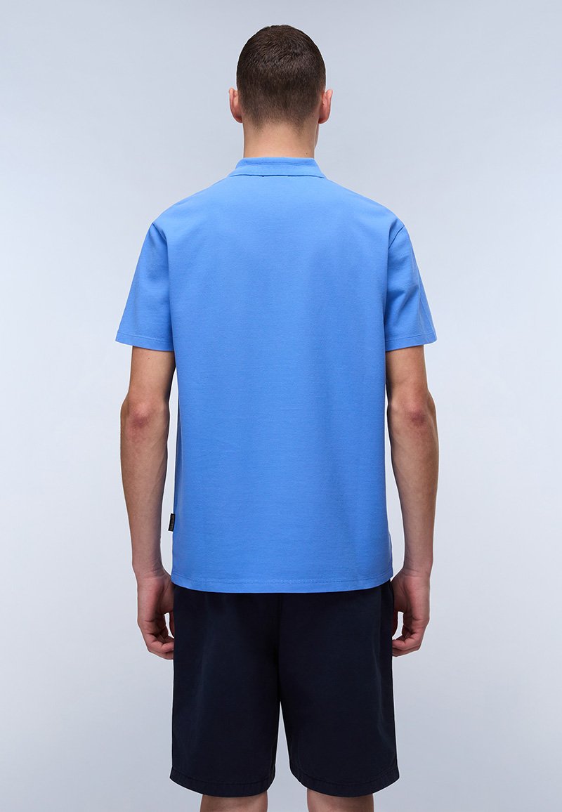 Polo shirt bleu clair à manches courtes en tissu lisse, avec un col standard et un ourlet droit, porté avec un short sombre.