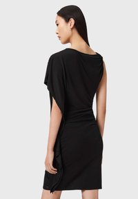 Mustapuku, jossa on laskostettu kangas ja lyhyet hihat, virtaava muotoilu ja sileä pinta, polvipituinen ja hillityt yksityiskohdat helman kohdalla.