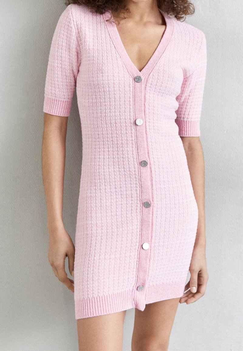 Abito lavorato a maglia rosa a maniche corte con scollo a V, texture a costine e bottoni argentati lungo la parte anteriore. Silhouette aderente con lunghezza leggermente sopra il ginocchio.