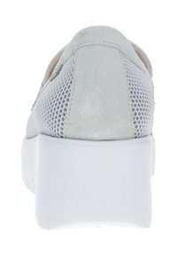 Zapatilla blanca con un acabado de ante suave y acentos de malla, con una suela blanca gruesa y un diseño minimalista. La vista trasera resalta el contraste de texturas.