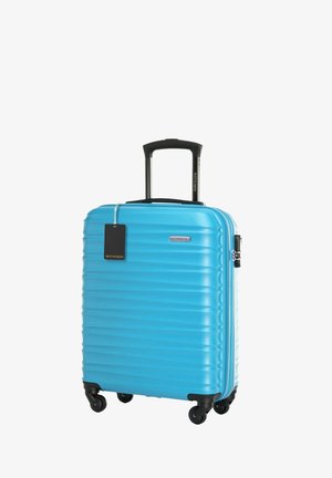 Valigia rigida di un vivace blu, con texture a righe, manico nero retrattile e quattro ruote per una facile mobilità.