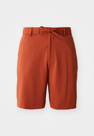 Orange textured shorts with a woven pattern, featuring a front tie waistband and side pockets. Classic fit and knee-length design.