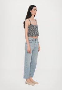 Grå og hvit mønstret cropped tank-top med tynne stropper, sammen med lyseblå høytlivsjeans og beige flats.