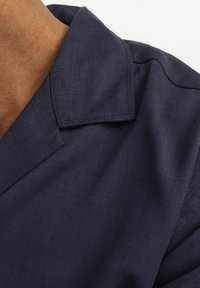 Navy blue collared shirt made of smooth fabric, featuring a clean-cut collar, subtle sheen, and stitching along the edges.