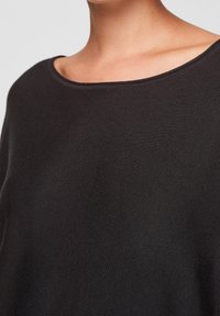 Czarny sweter z szerokim, okrągłym dekoltem i prążkowaną fakturą. Krótkie rękawy i luźny krój podkreślają nowoczesny design.