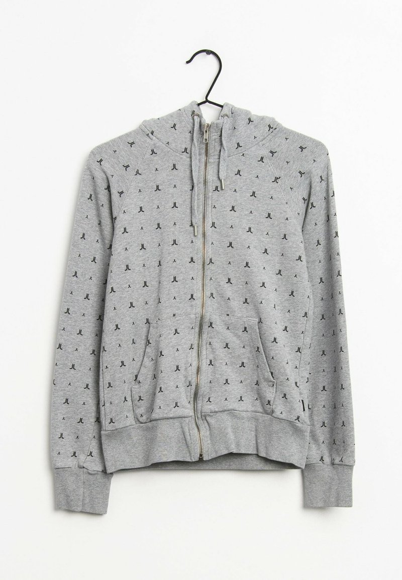 Sweat à zip gris avec capuche, poches avant et un motif répétitif en petites lettres noires. Fabriqué en tissu doux et texturé.