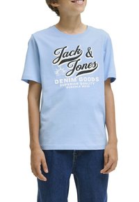 Camiseta de algodón azul claro con el texto "Jack & Jones" en blanco y negro, con mangas cortas y un corte relajado, combinada con jeans de mezclilla azules.