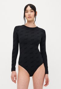 Dlouhý černý body z měkkého materiálu s jemným vzorem loga po celé ploše a přiléhavým střihem.