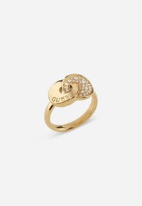 Gold-tone ring featuring a twisted design with embedded clear crystals. Engraved "GUESS" on one side, smooth finish, round band.