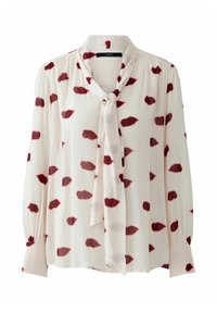 Langärmlige Bluse in hellem Creme mit Bindekragen, ausgestattet mit roten Lippen-Muster und gerafften Ärmeln für eine strukturierte Optik.