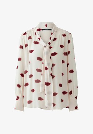 Langärmlige Bluse in hellem Creme mit Bindekragen, ausgestattet mit roten Lippen-Muster und gerafften Ärmeln für eine strukturierte Optik.