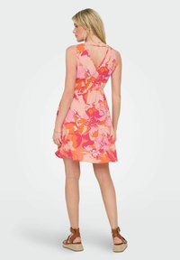 Vestido floral con diseño de espalda en V, que presenta patrones brillantes en rosa y naranja. Hecho de tejido ligero, ceñido en la cintura, de longitud hasta larodilla.