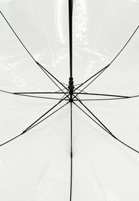 Weißer Regenschirm von unten betrachtet, der ein glänzendes, transparentes Dach sowie ein schwarzes Metallgestell mit Speichen und einem zentralen Pole aufweist.