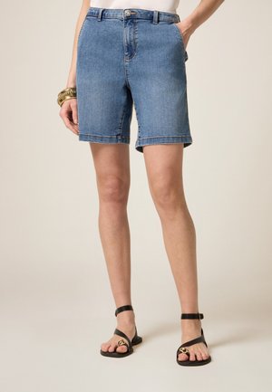 Denim shorts met een lichtblauwe wassing, met een hoge taille, opgerolde zomen en voorzakken. Gepaard met zwarte sandalen met bandjes.