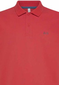Polo rosso realizzato in cotone, con colletto classico, chiusura a due bottoni e un piccolo logo grigio del marchio sul lato sinistro del petto.