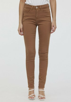 Jean skinny marron taille haute, fabriqué dans un matériau doux et extensible. Il dispose de deux poches avant et de détails de couture subtils le long des coutures.