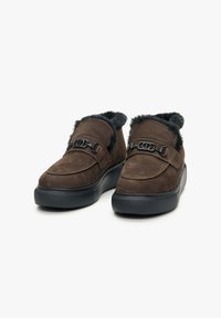 Brown suede slip-on shoes with black faux fur collar, featuring decorative black buckle accents and textured rubber soles.