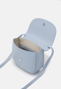 Světlomodrá kabelka s hladkou texturou, magnetickým zapínáním, vnitřními přihrádkami na karty a odnímatelným ramenním popruhem. Otevřený design odhaluje úložný prostor.