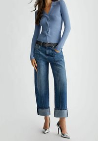 Ljusblå ribbad cardigan med V-ringning och knäppt front. Matchad med mörkblå vida jeans med uppvikt fåll och silverfärgade klackar.