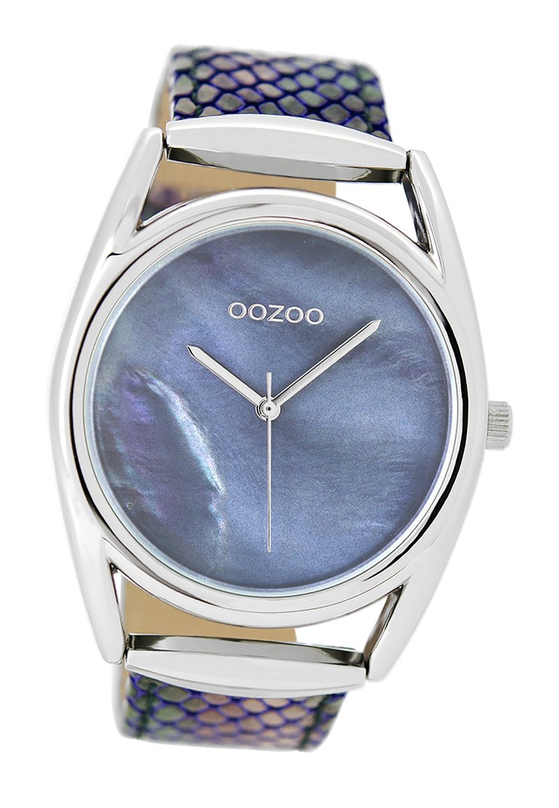 Montre argentée avec un cadran rond bleu irisé et des aiguilles argentées. Le bracelet présente un motif texturé violet et vert.