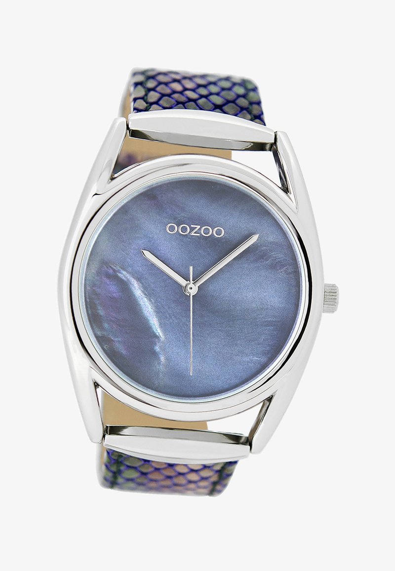 Montre argentée avec un cadran rond bleu irisé et des aiguilles argentées. Le bracelet présente un motif texturé violet et vert.