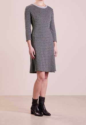 Robe grise midi avec un motif texturé, manches trois-quarts et col rond, accompagnée de bottines noires.