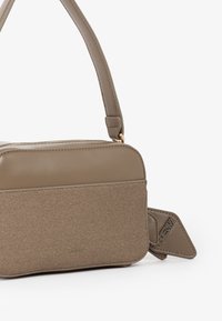 Piccola borsa a tracolla rettangolare con parte superiore in pelle taupe, parte anteriore in tessuto testurizzato e tracolla regolabile su sfondo bianco.
