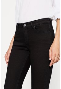 Czarne dżinsy wykonane z denimu, o slim fit, z pięcioma kieszeniami i srebrnym guzikiem na wysokości talii. Gładka tekstura, bez widocznych wzorów.