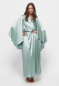 Pitkä, vaaleansininen satiinimekko, jossa on laskeutuvat hihat, pehmeä pinta ja suora siluetti. Mekossa on rypytetty vyötärö ja elegantti laskos.