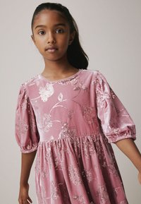 Roze fluwelen jurk met pofmouwen, voorzien van bloemenpaillettenpatronen, een ronde halslijn en een geplooide taille voor een volle rok.