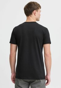 Svart t-skjorte med kort erm, laget av bomull, med rund hals og en glatt tekstur. Ingen synlige mønstre eller logoer. Baksidevisning vist.