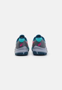 Scarpe da ginnastica grigie con accenti blu e rosa, upper in rete, suola ammortizzata e battistrada testurizzato. Vista da dietro con un design del tallone arrotondato.