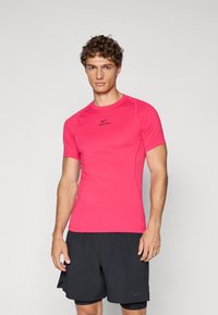 Camiseta atlética de manga corta en color rosa con un diseño ajustado, que presenta un logo negro de Nike Pro. Tejido texturizado y ligero, adecuado para el deporte.