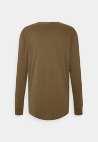 Haut à manches longues en coton marron, doté d'un col rond et d'un ourlet incurvé. Les manches se terminent par des poignets ajustés. Aucune motif ou accent visible.